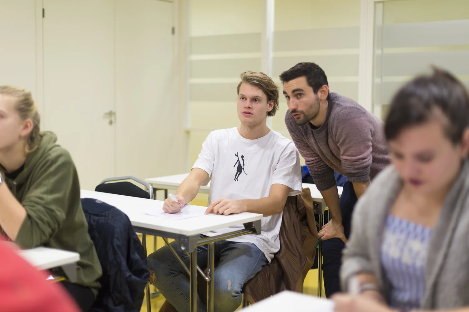 Karim hjelper en elev en-til-en ved pulten